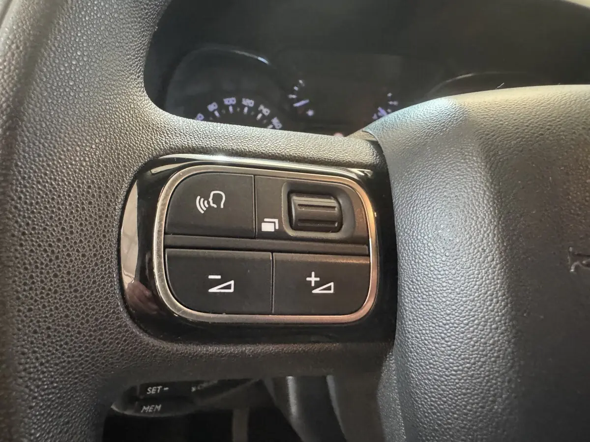 Gros plan sur les commandes multifonctions noires du volant du Citroën Berlingo blanc, version 2020.