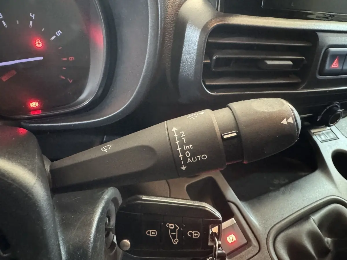 Gros plan sur la commande d’essuie-glace à gauche du volant dans l’habitacle du Citroën Berlingo blanc 2020.