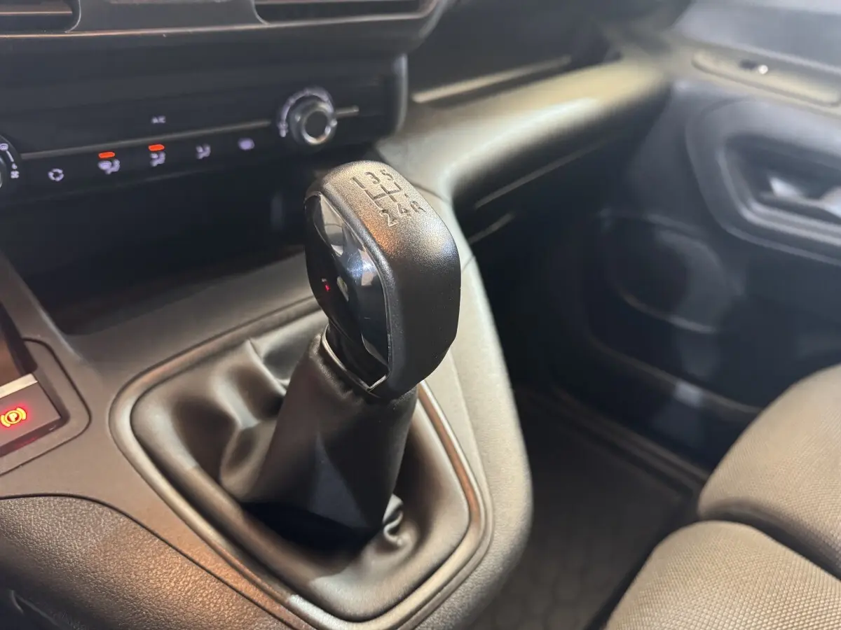Gros plan sur le levier de vitesses manuel noir dans l’habitacle du Citroën Berlingo blanc, côté passager.