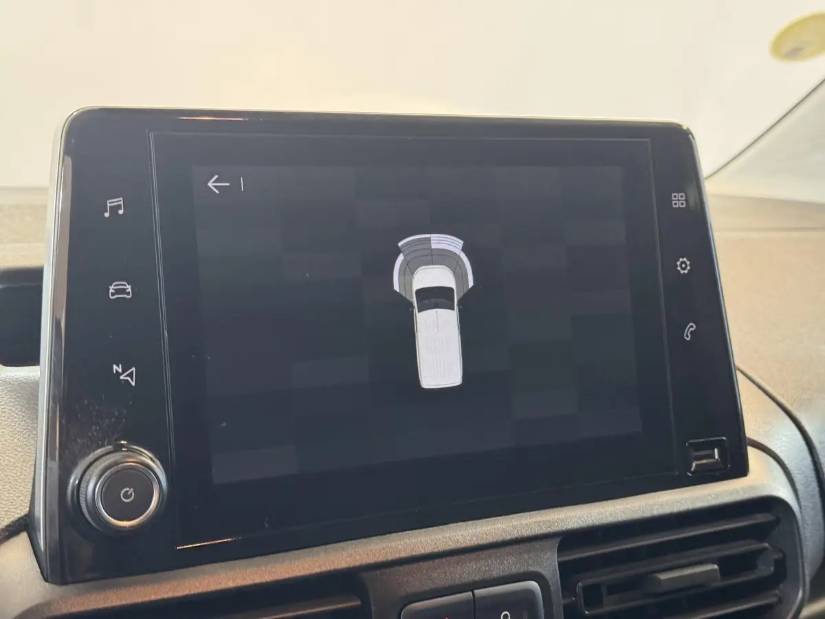 Écran tactile central affichant l'aide au stationnement du Citroën Berlingo blanc, vue intérieure du tableau de bord.