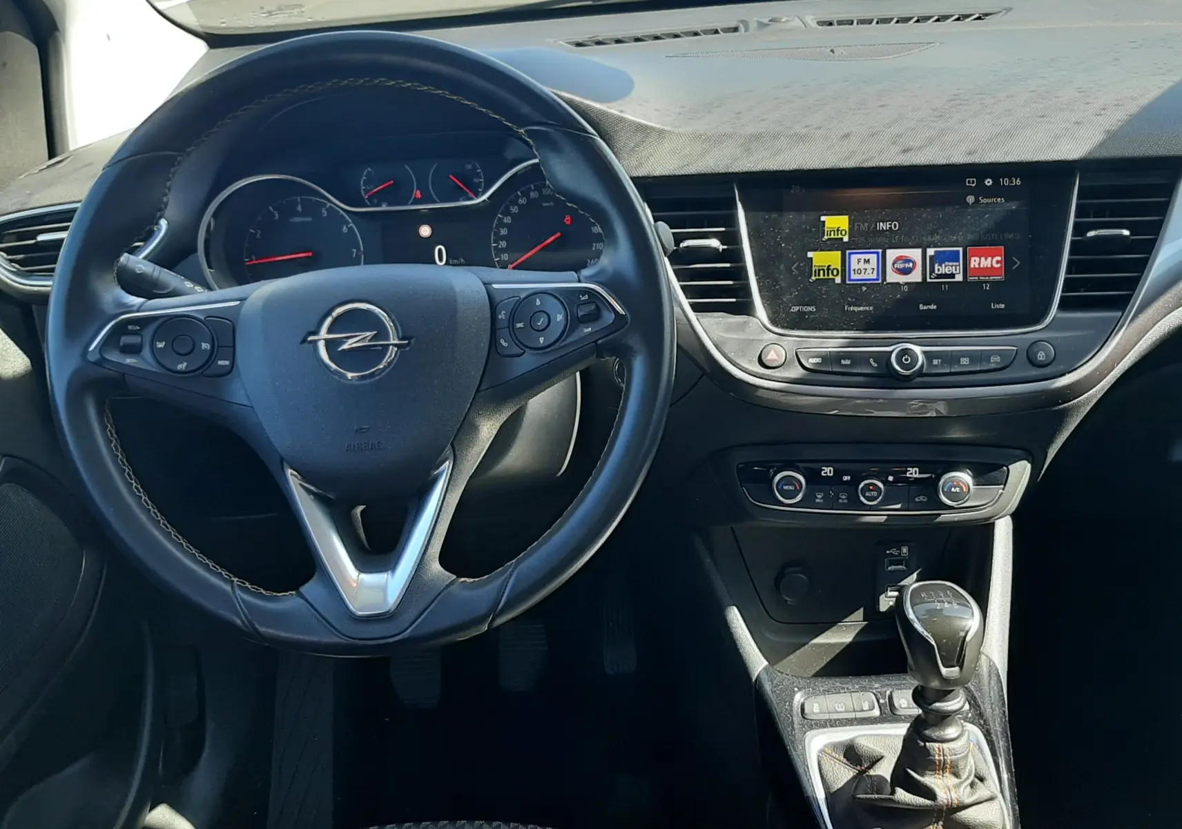 Vue intérieure avant centrée sur le volant noir et la console centrale d'une Opel Crossland X 130ch Innovation 2019.