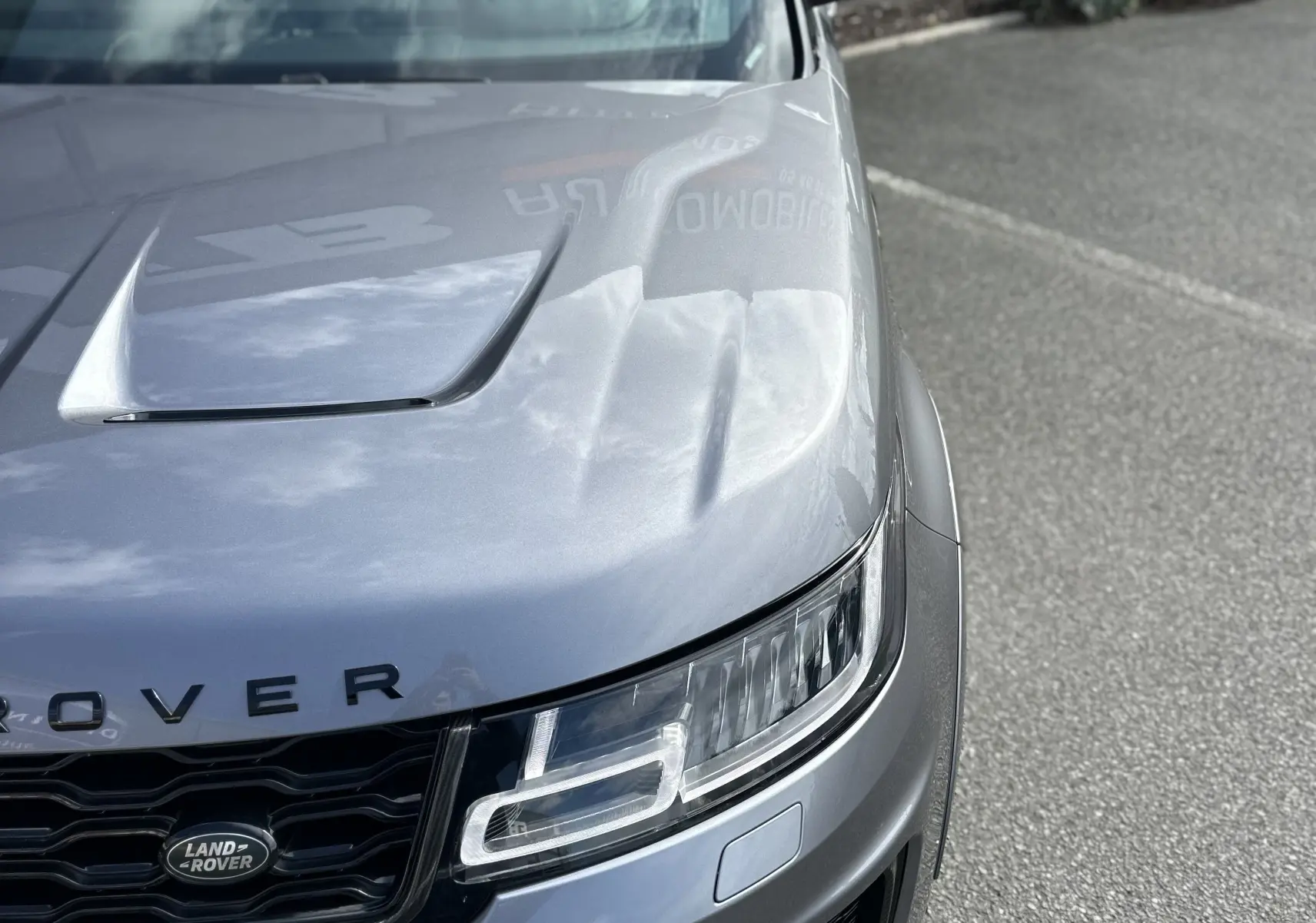 Vue 3/4 avant droit d'un Range Rover Sport gris foncé 2020 avec capot sculpté et calandre noire distinctive.