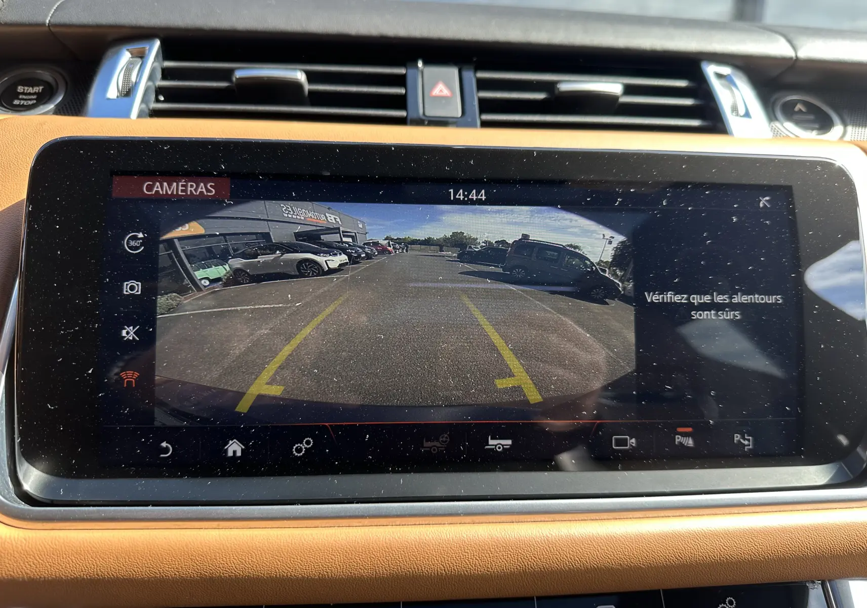 Vue de l'écran tactile intérieur du Range Rover Sport 2020 montrant la caméra de recul avec lignes de guidage jaunes.