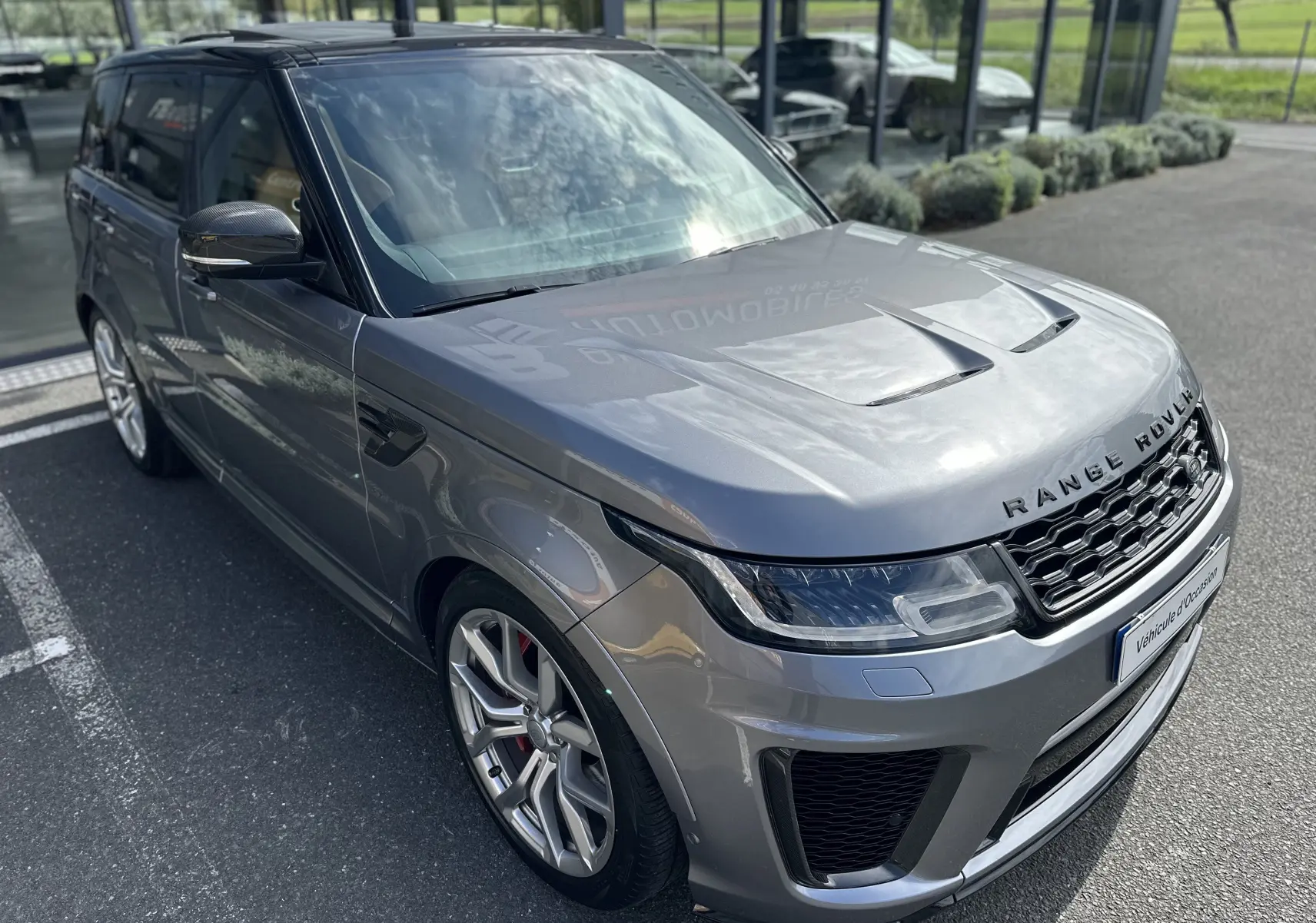 Vue 3/4 avant gauche d'un Range Rover Sport SVR Carbon Edition gris foncé avec jantes alliage et détails carbone sur les rétroviseurs.