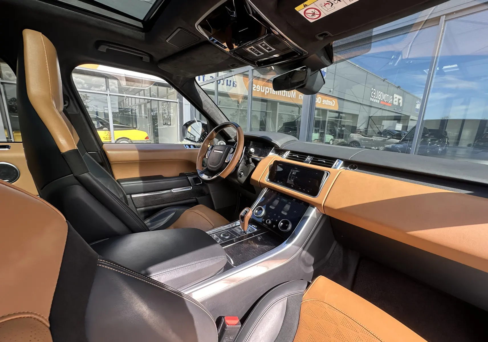 Vue intérieure côté conducteur du Range Rover Sport II V8 5.0 Supercharged SVR Carbon Edition 2020 avec sellerie cuir marron et noir.