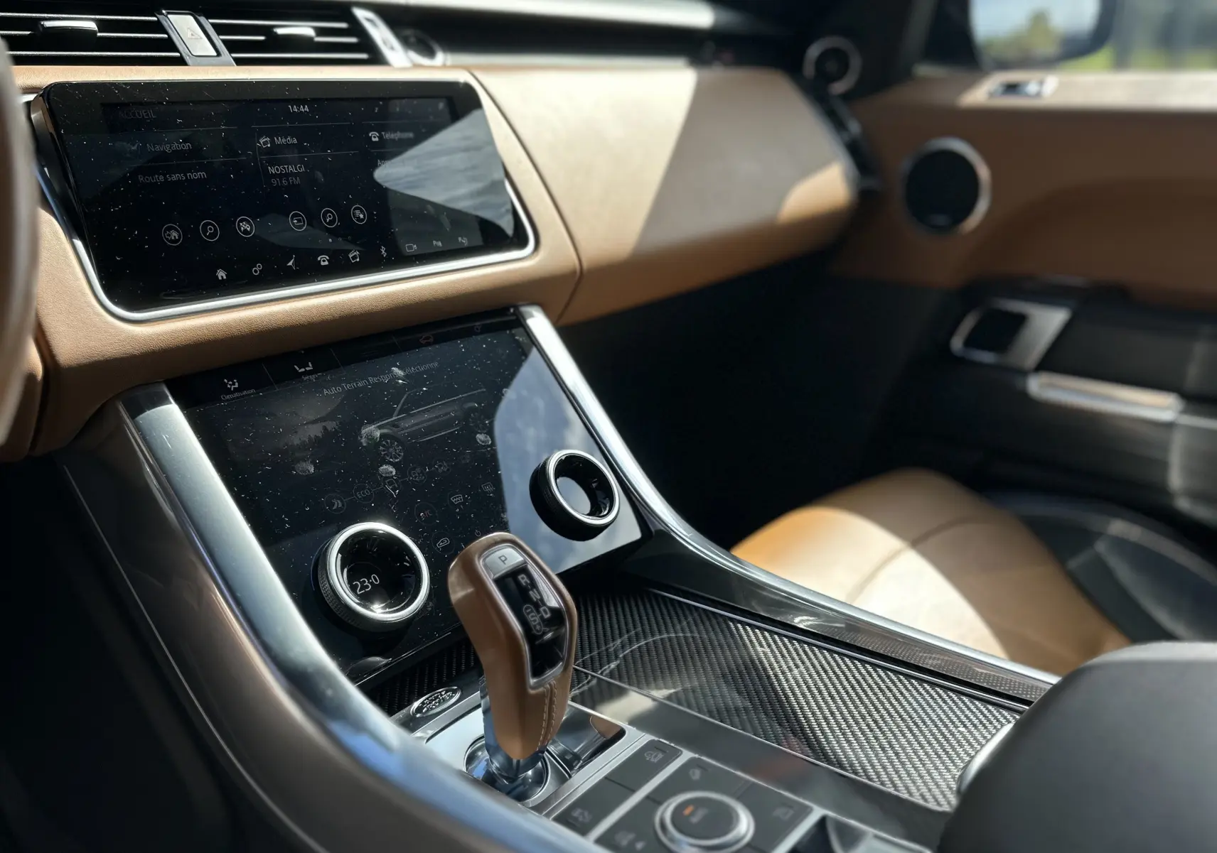 Intérieur du Range Rover Sport SVR 2020 vu côté passager, avec console centrale en carbone et sellerie beige.