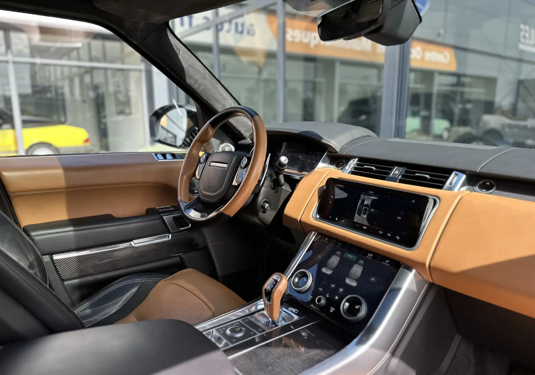 Vue intérieure côté conducteur du Range Rover Sport SVR 2020, cuir marron et noir, tableau de bord moderne avec écran tactile.