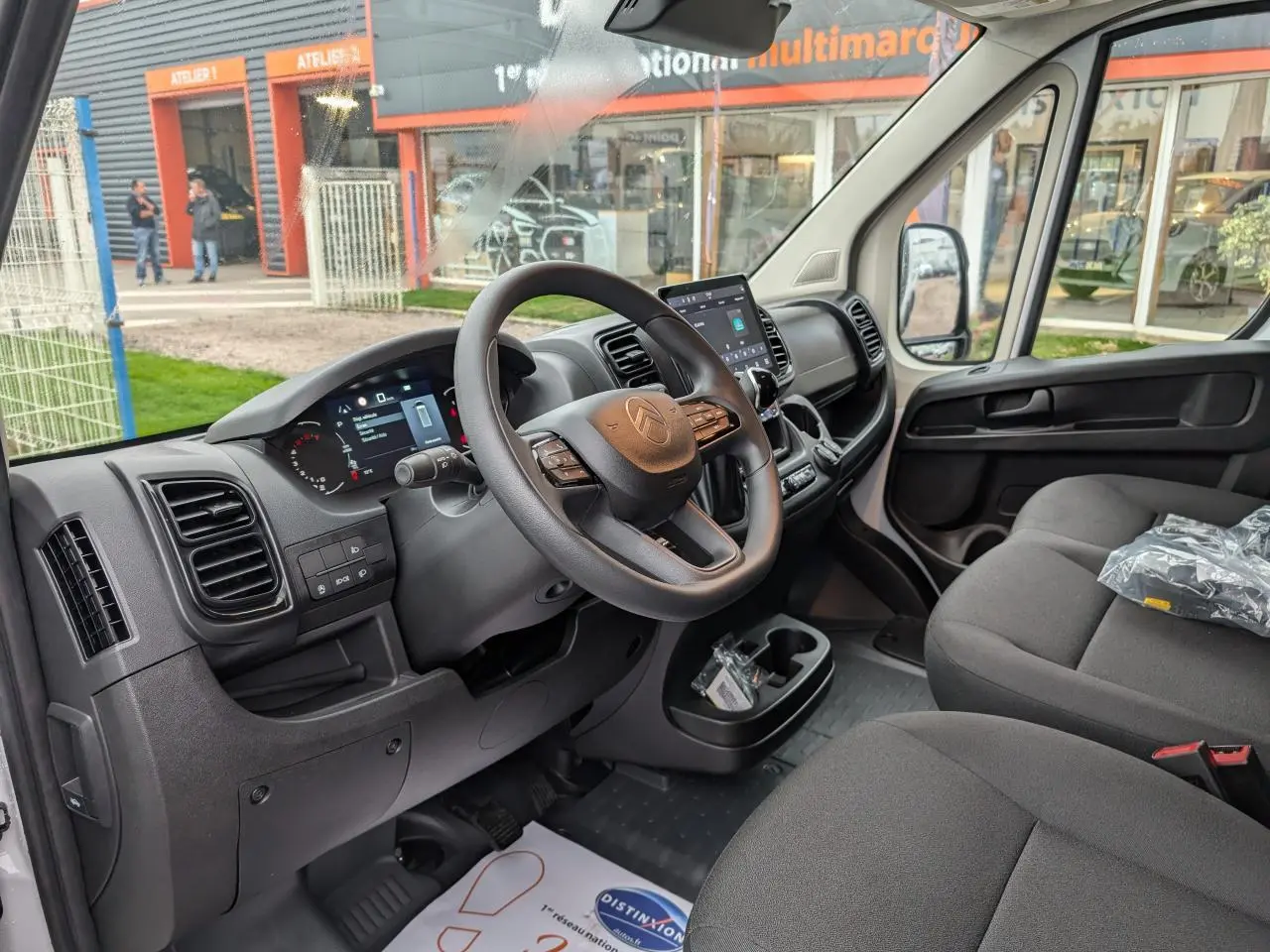 Intérieur avant droit du Citroën Jumper blanc 2025 montrant tableau de bord numérique et sièges tissu noir.