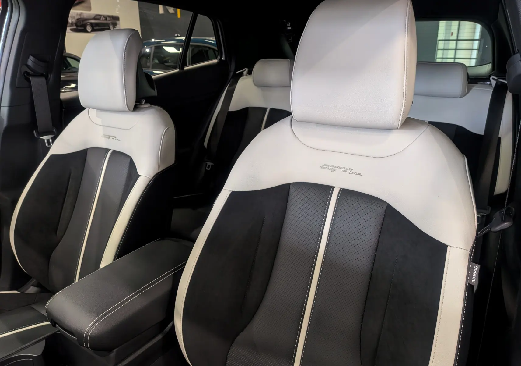 Vue rapprochée des sièges avant bi-ton noir et blanc du Kia Sportage GT Line 2025 avec logo brodé sur appuie-tête.