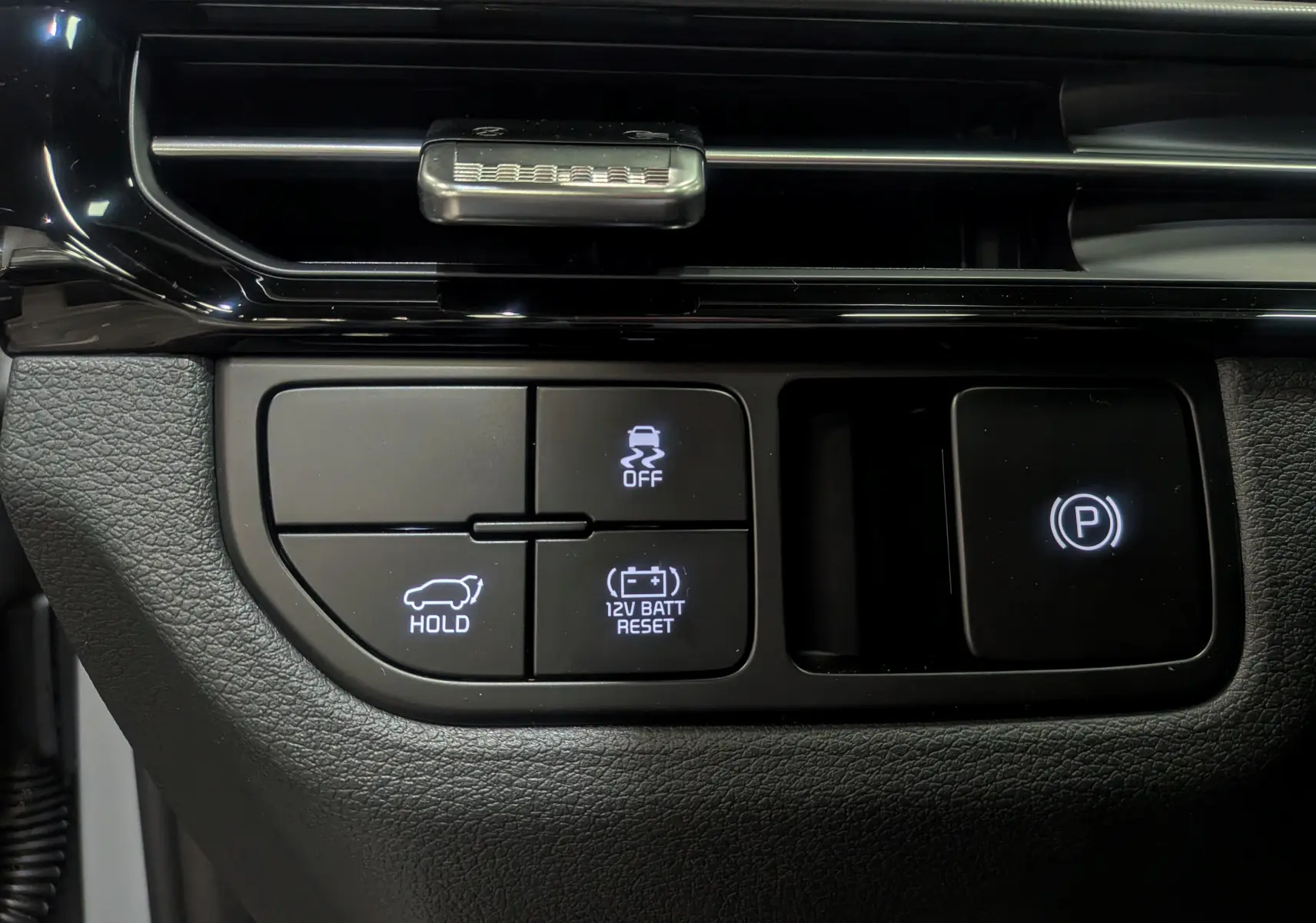 Boutons de commande du frein à main électrique et fonctions d'assistance sur le tableau de bord du KIA SPORTAGE gris céramique 2025.