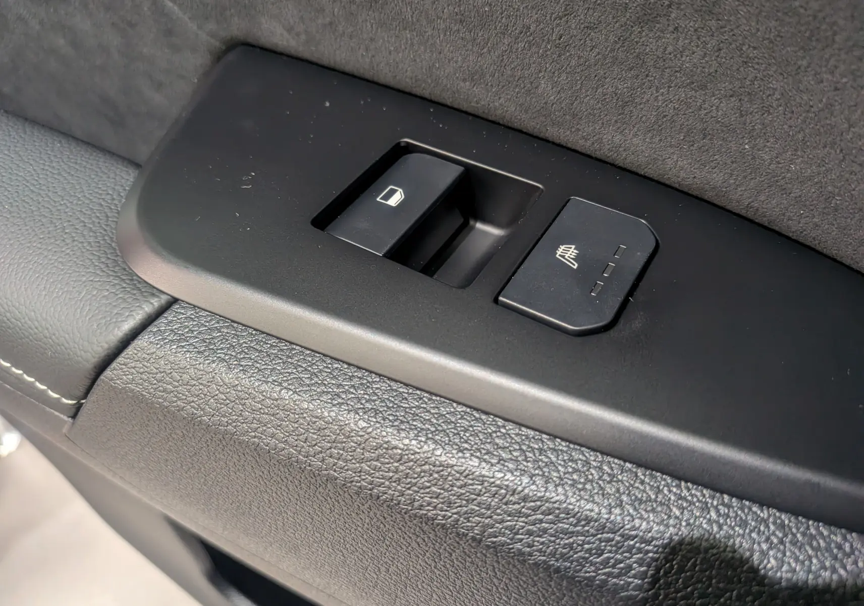 Gros plan sur les commandes de la porte côté conducteur du KIA SPORTAGE gris céramique avec toit noir, version 2025.