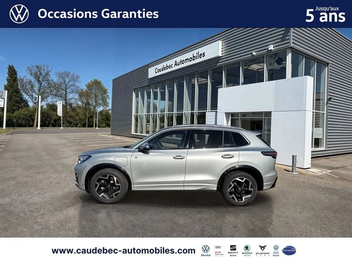 Volkswagen Tiguan eHybrid argent Dolomite vu de profil côté gauche, avec jantes noires et toit ouvrant panoramique.