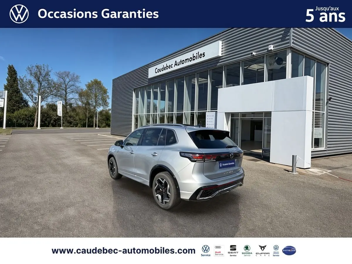 Vue 3/4 arrière droite d’un Volkswagen Tiguan 2025 argent Dolomite, avec jantes 19 pouces et toit ouvrant panoramique visible.
