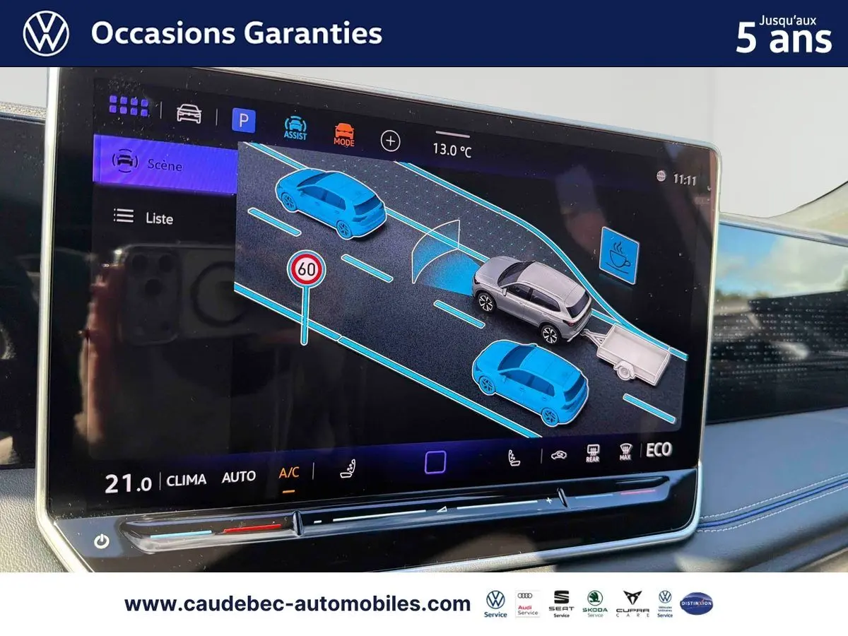 Écran tactile intérieur montrant l'assistant de conduite avec représentation du Volkswagen Tiguan argent Dolomite et remorque.