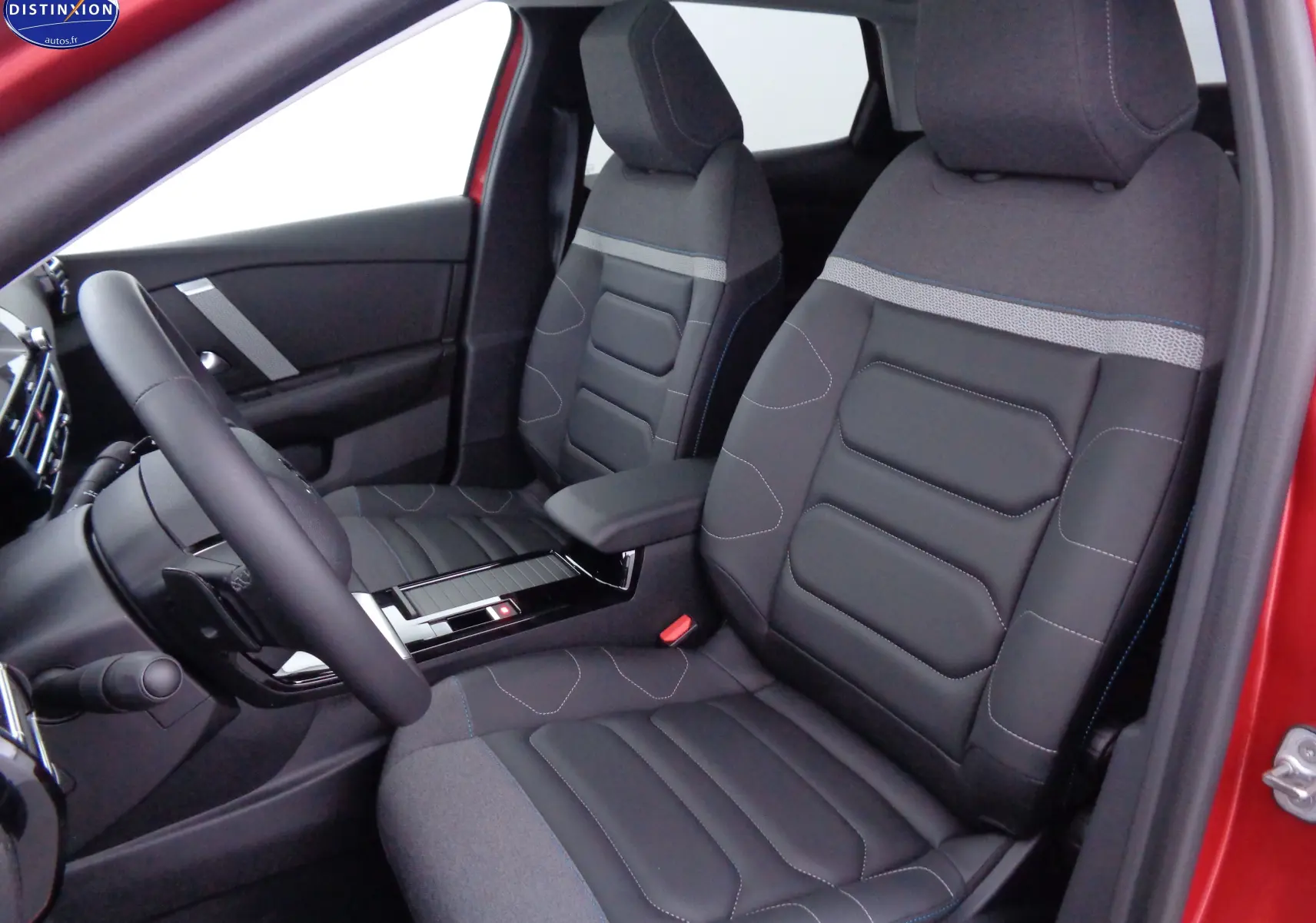 Vue intérieure côté conducteur de la Citroën C4 X rouge Elixir, sièges mixtes tissu et cuir noir avec surpiqûres bleues.