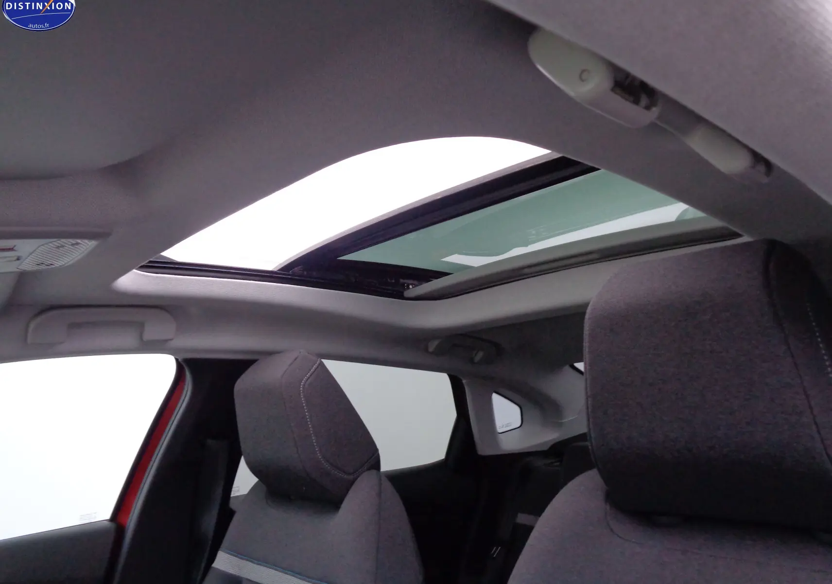 Toit ouvrant panoramique ouvert sur l'intérieur gris foncé d'une Citroën C4 X rouge Elixir Metal, vue côté gauche arrière.
