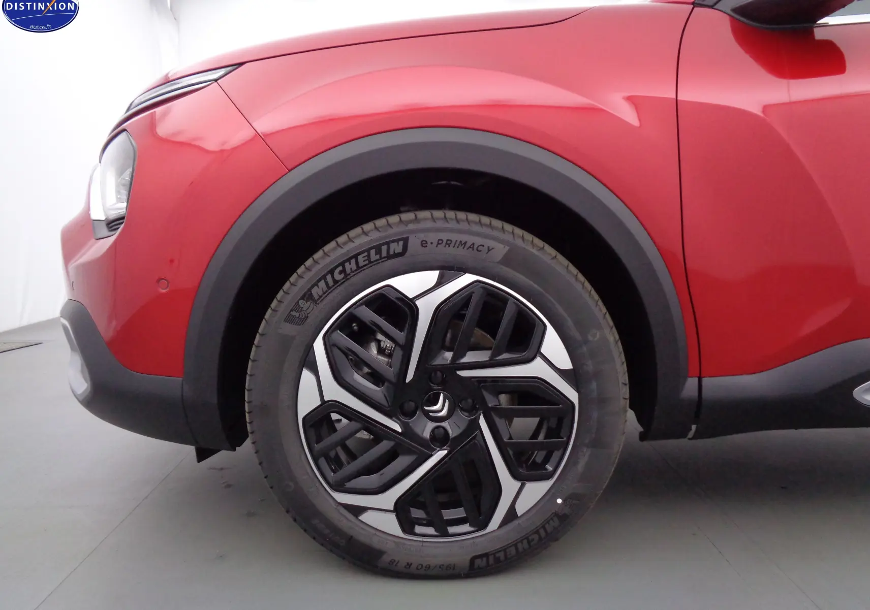 Gros plan sur la roue avant gauche de la Citroën C4 X rouge Elixir Metal, mettant en valeur la jante noire et argentée au design moderne.