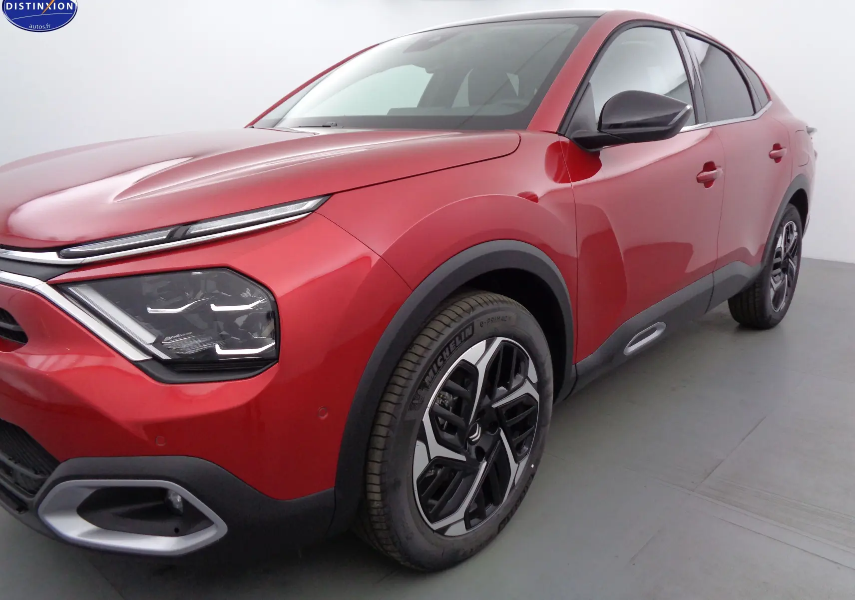 Vue 3/4 avant droit d'une Citroën C4 X rouge Elixir métal avec phares LED et jantes alliage bicolores.