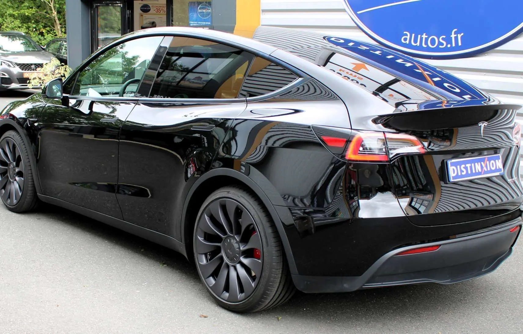 Tesla Model Y Performance noir métal vue 3/4 arrière droit, jantes noires et feux arrière LED distinctifs.