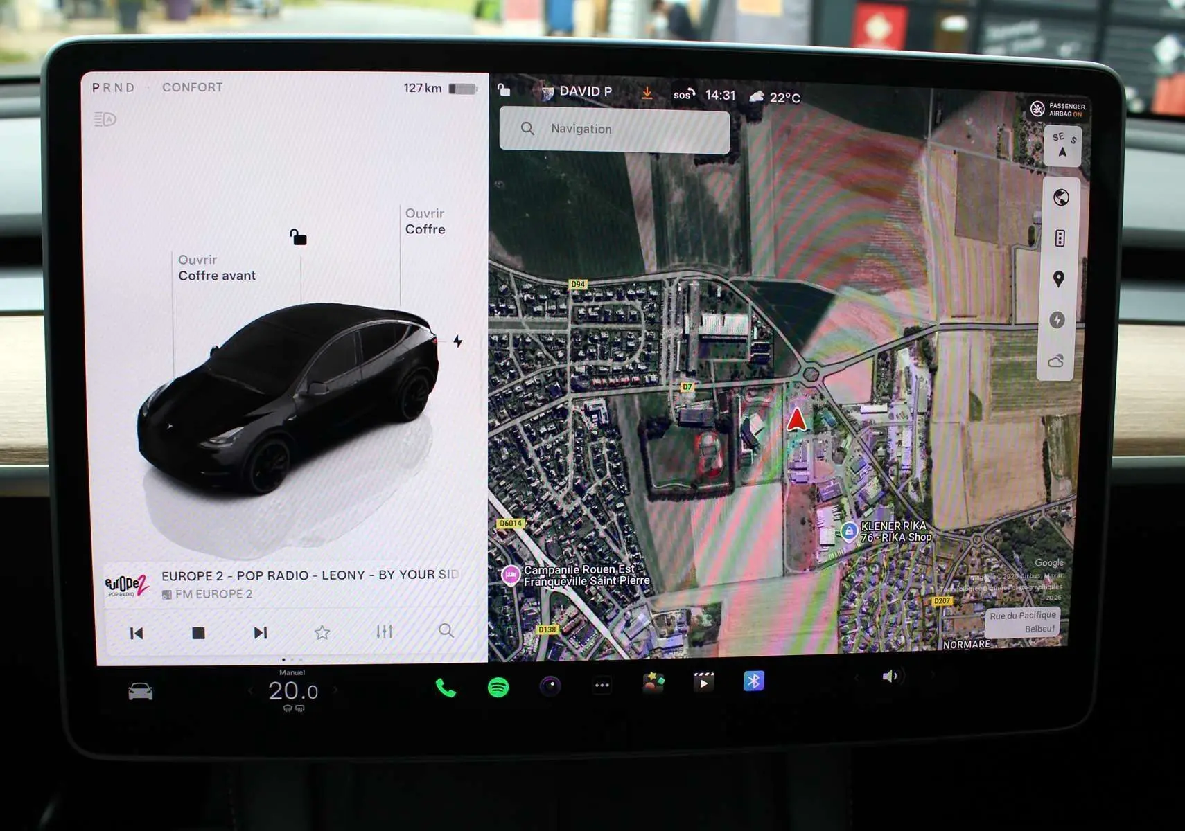 Écran tactile central affichant la Tesla Model Y noire métal en vue 3/4 arrière avec carte GPS et options ouvertes.