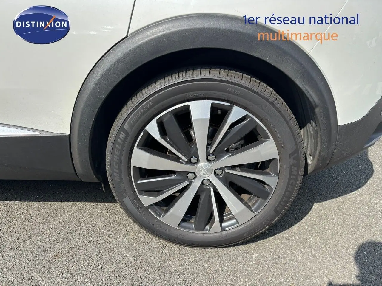 Gros plan sur la roue avant droite d'un Peugeot 3008 blanc nacré avec jante alliage bicolore moderne.