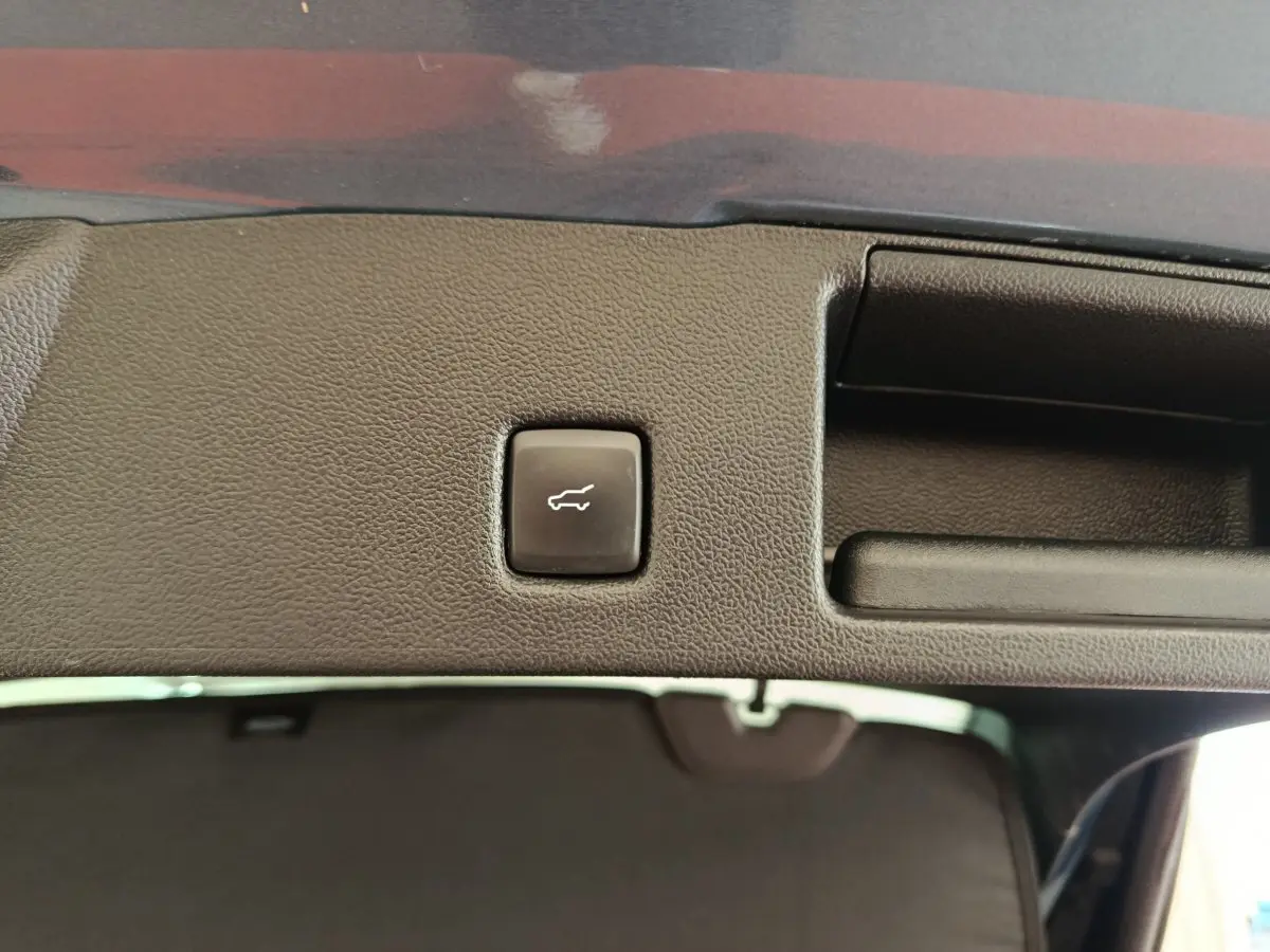 Bouton d'ouverture électrique du coffre sur la partie intérieure de la porte arrière du Ford Kuga bleu 2024.