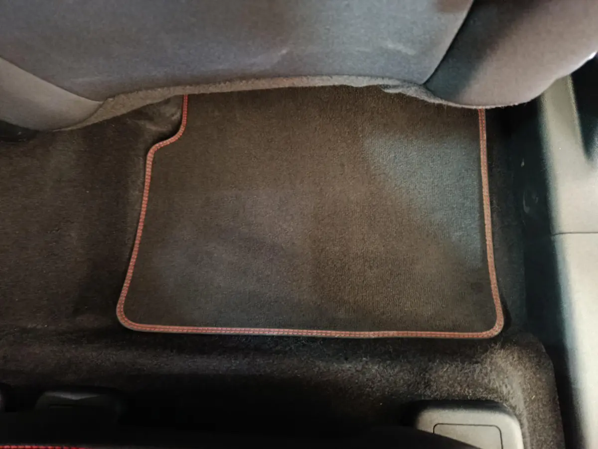 Tapis de sol noir avec surpiqûres rouges dans l'habitacle arrière du Ford Kuga 2024 St Line bleu.