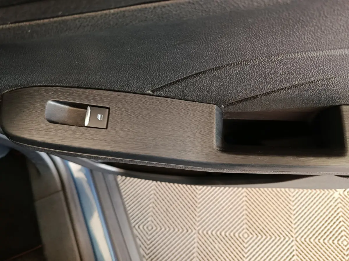 Gros plan sur la poignée intérieure côté gauche du Ford Kuga bleu 2024 avec bouton de verrouillage intégré.