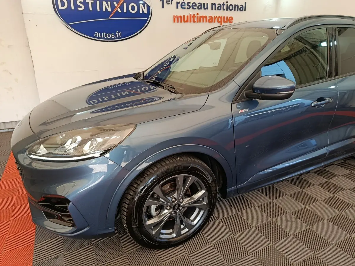 Vue 3/4 avant gauche d'un Ford Kuga bleu 2024 avec jantes alliage et badge St Line sur aile avant.