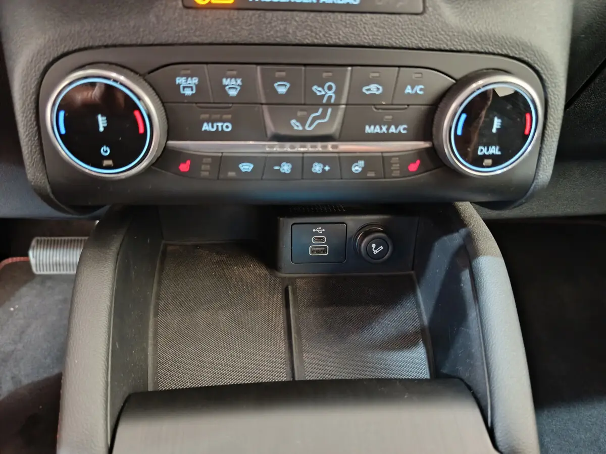 Vue rapprochée du panneau de commande de climatisation bicolore et ports USB du Ford Kuga 2024 intérieur noir.