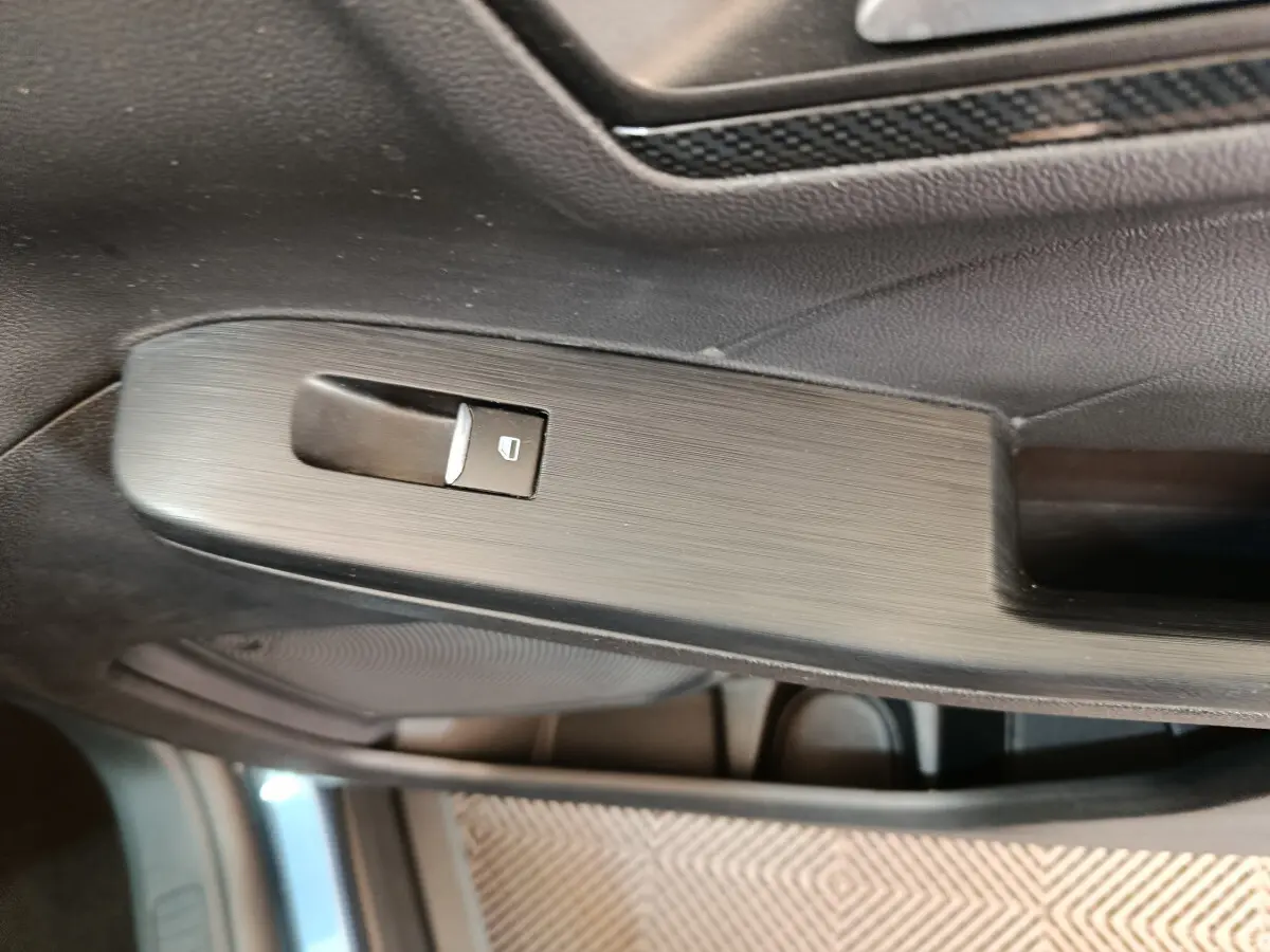 Gros plan sur la commande de lève-vitre côté gauche dans l'habitacle du Ford Kuga bleu 2024 St Line.