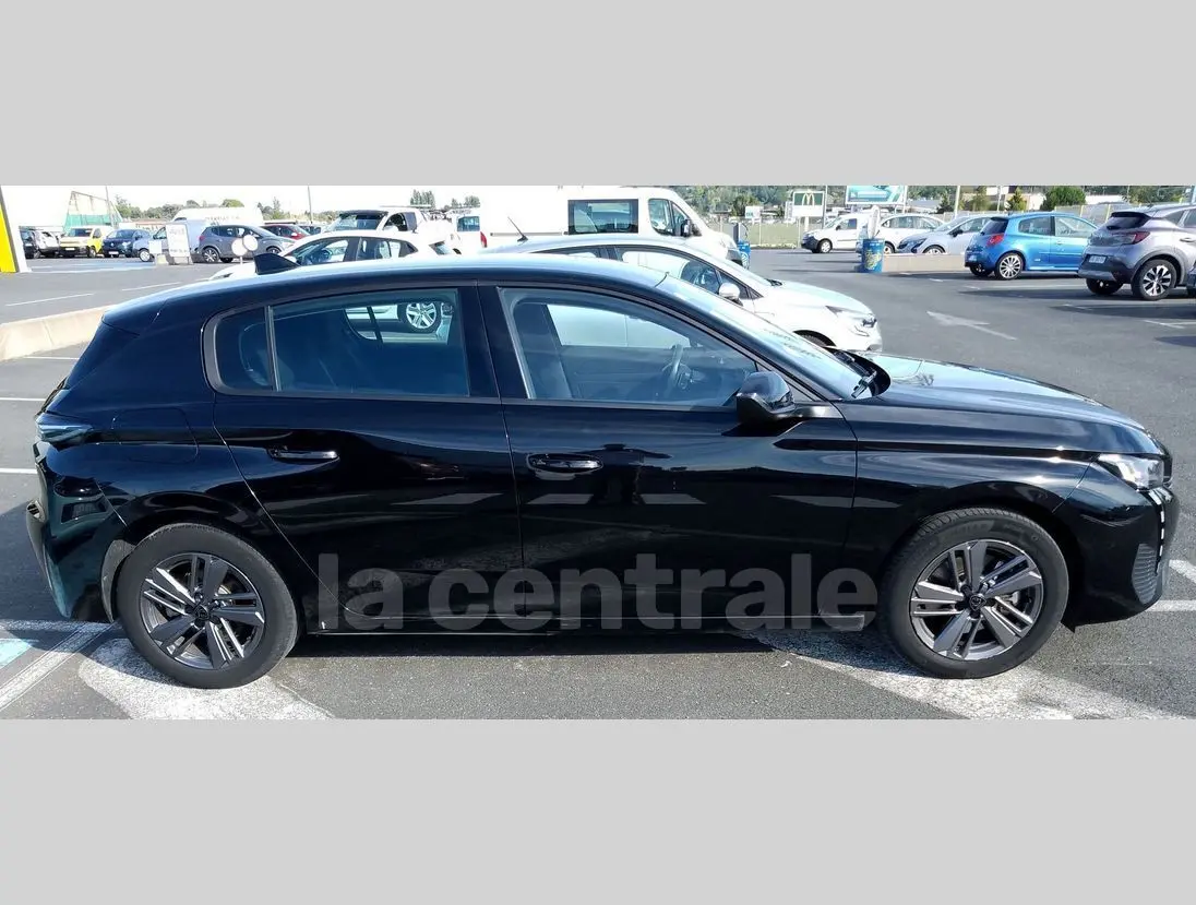 Profil côté gauche d'une Peugeot 308 noire de 2022, finition Active Pack, garée en extérieur sur un parking.