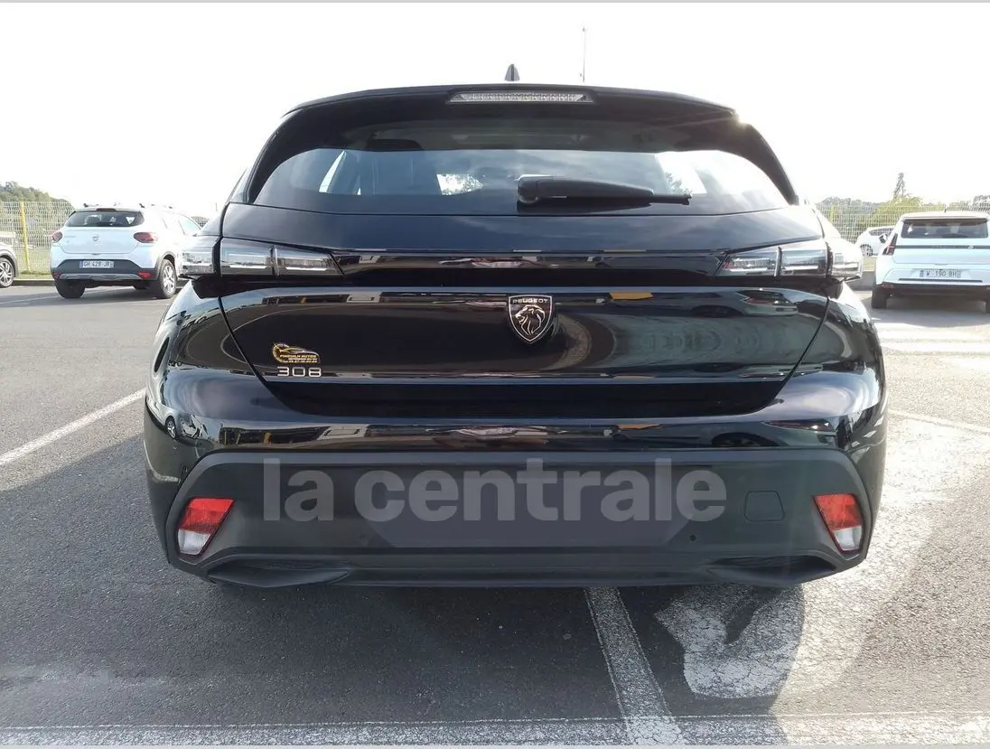 Vue arrière d'une Peugeot 308 noire 2022 avec logo lion et feux arrière étirés, stationnée en extérieur.