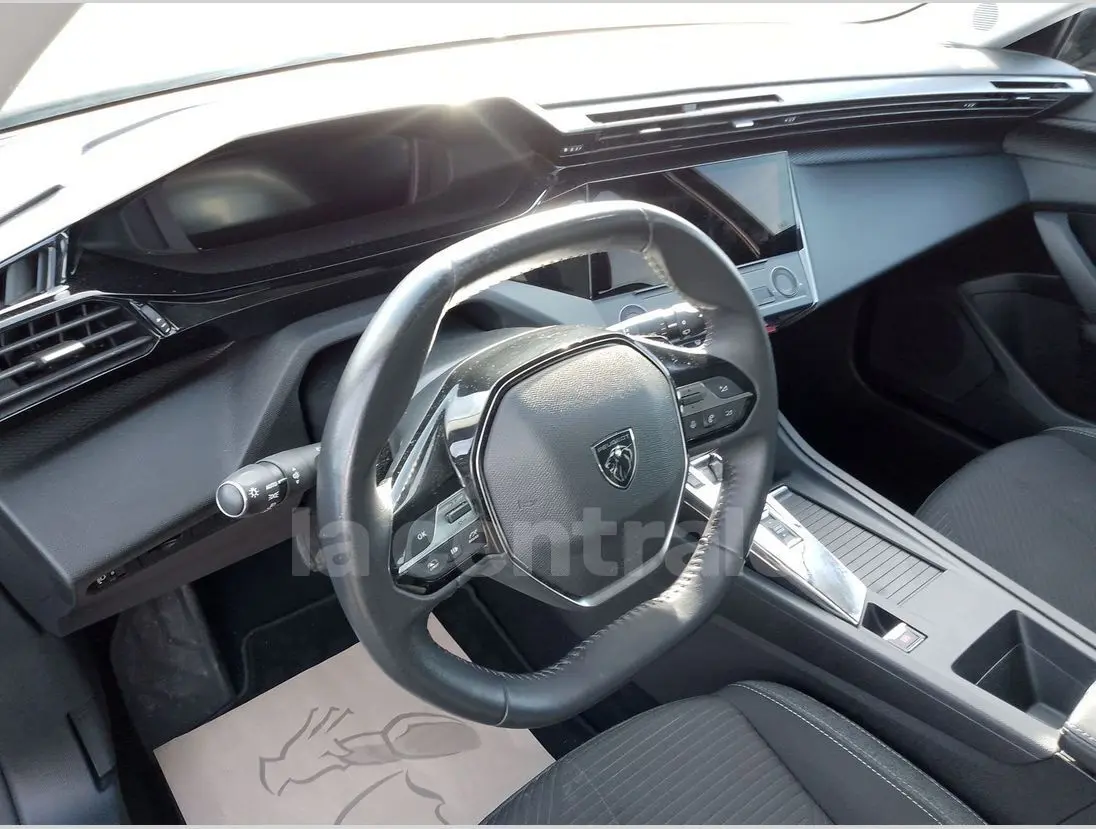 Vue intérieure du poste de conduite de la Peugeot 308 noire, avec volant cuir et tableau de bord moderne en 2022.