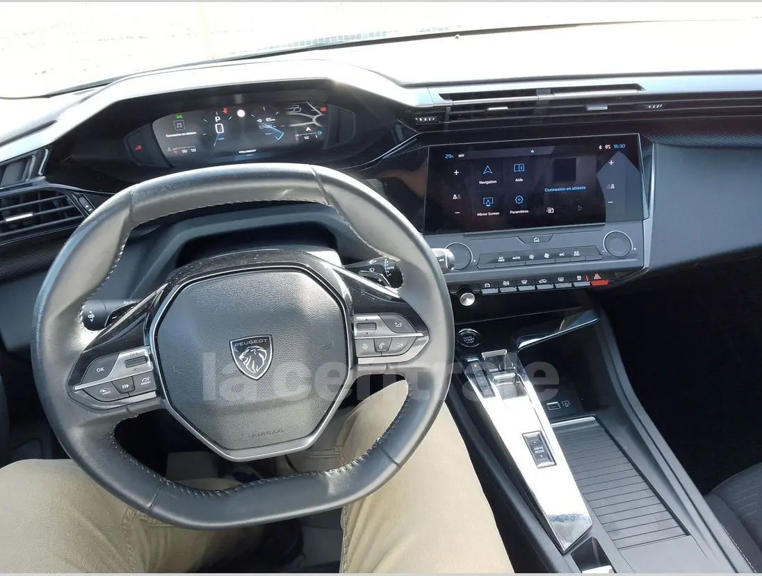 Vue intérieure centrée sur le volant cuir et le tableau de bord numérique de la Peugeot 308 noire de 2022.