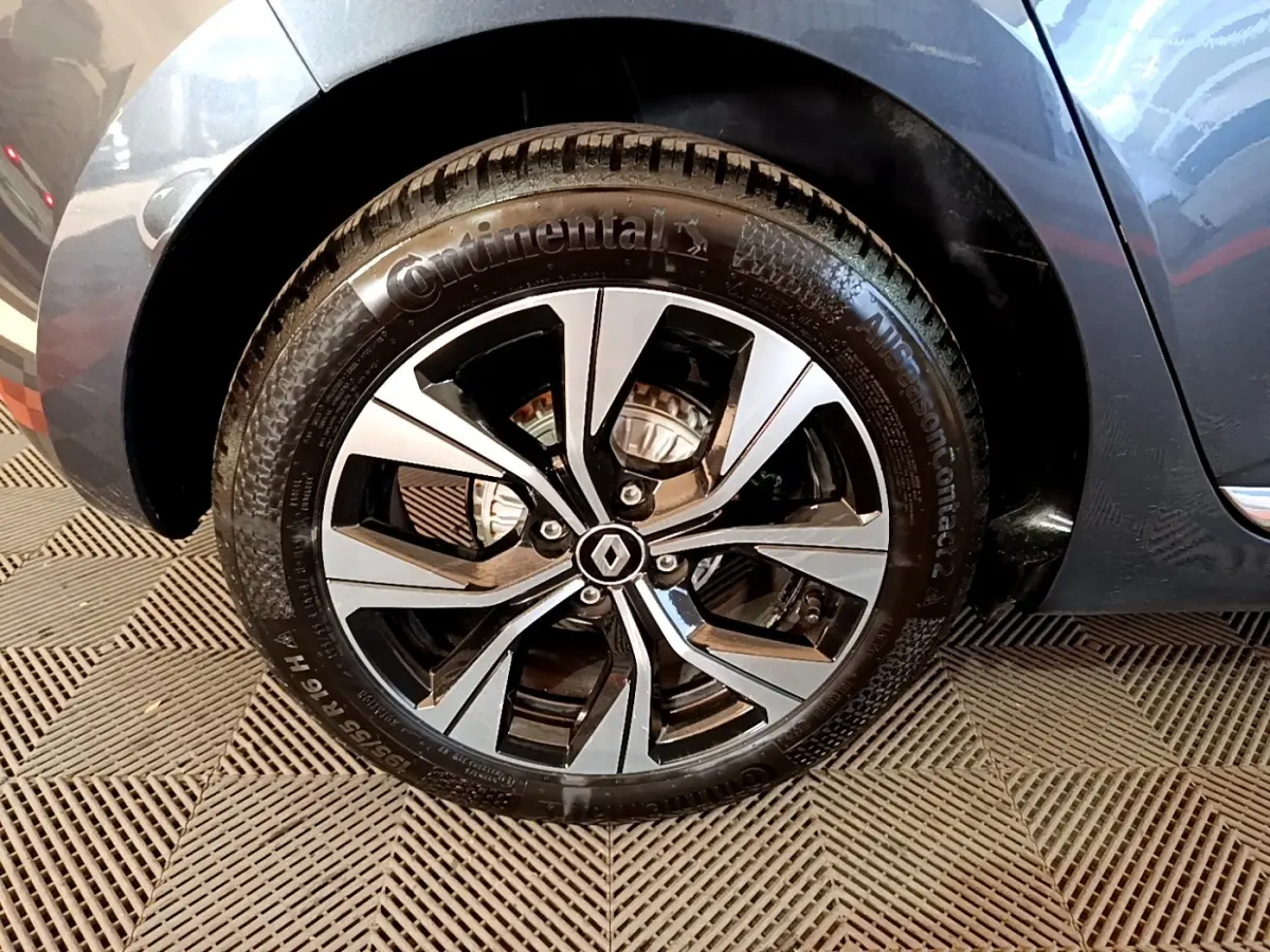 Gros plan sur la roue avant droite gris foncé de la Renault Clio Evolution SCe 65 avec jante alliage bicolore et logo Renault.