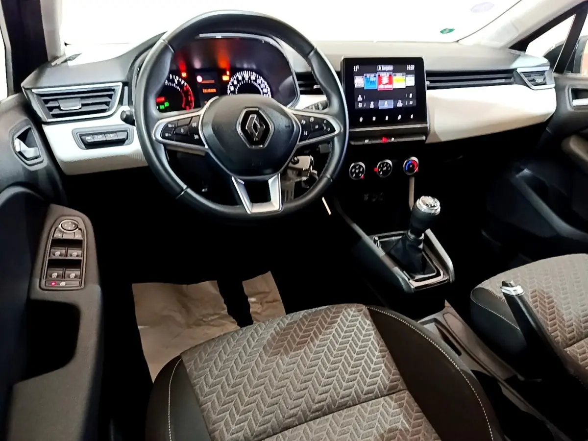 Vue intérieure avant de la Renault Clio gris foncé 2022, volant multifonctions, écran tactile central et boîte manuelle.