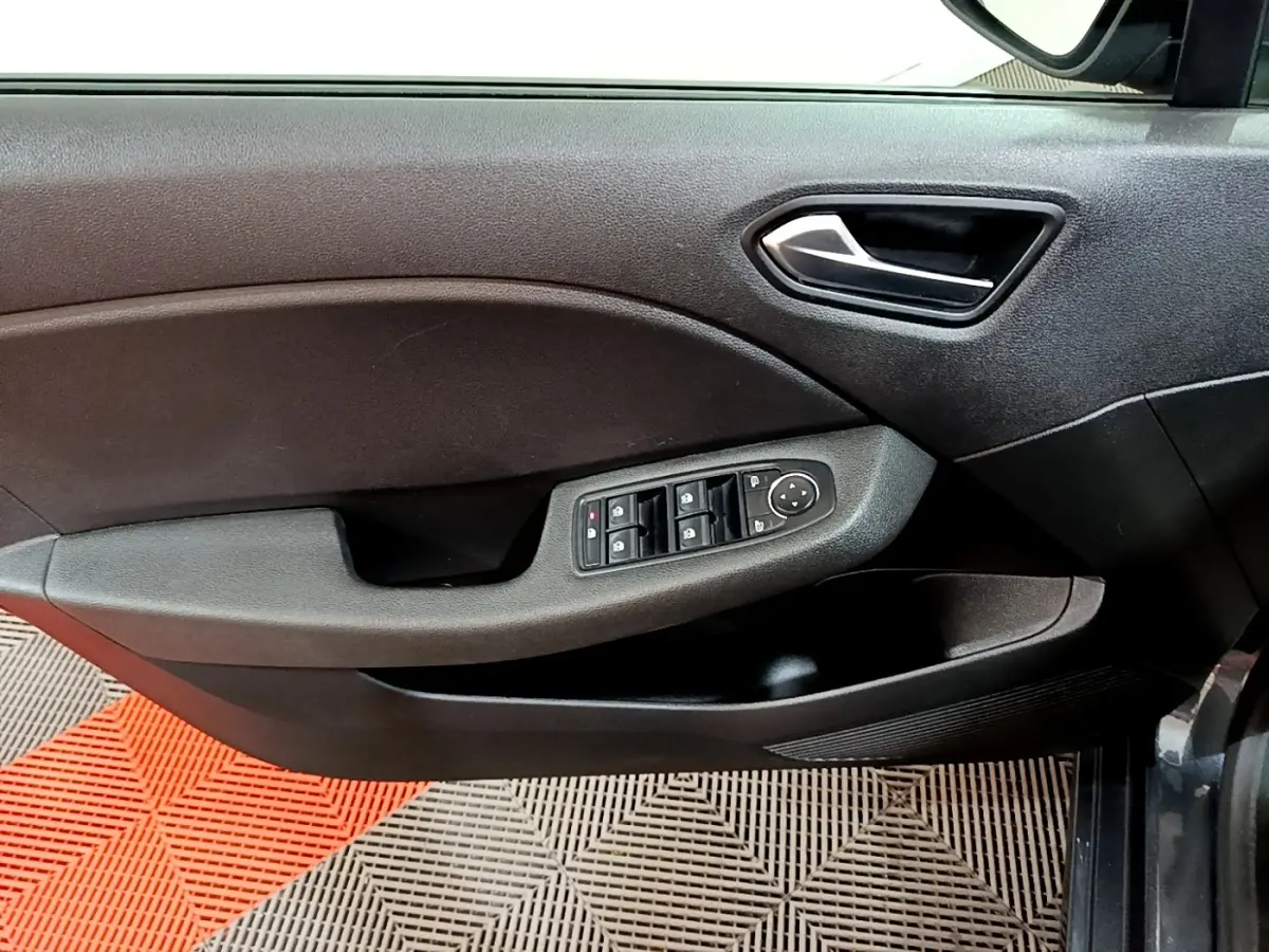 Vue intérieure côté gauche de la porte conducteur d'une Renault Clio gris foncé avec commandes de vitres et poignée métallique.