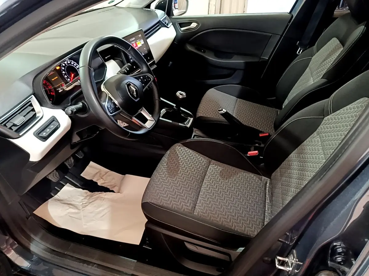 Vue intérieure côté conducteur de la Renault Clio gris foncé 2022, volant cuir, tableau de bord avec écran tactile.