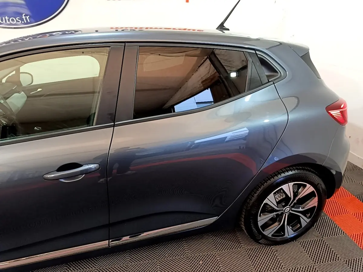 Vue latérale droite d'une Renault Clio gris foncé 2022, mettant en valeur les vitres teintées et les jantes modernes.