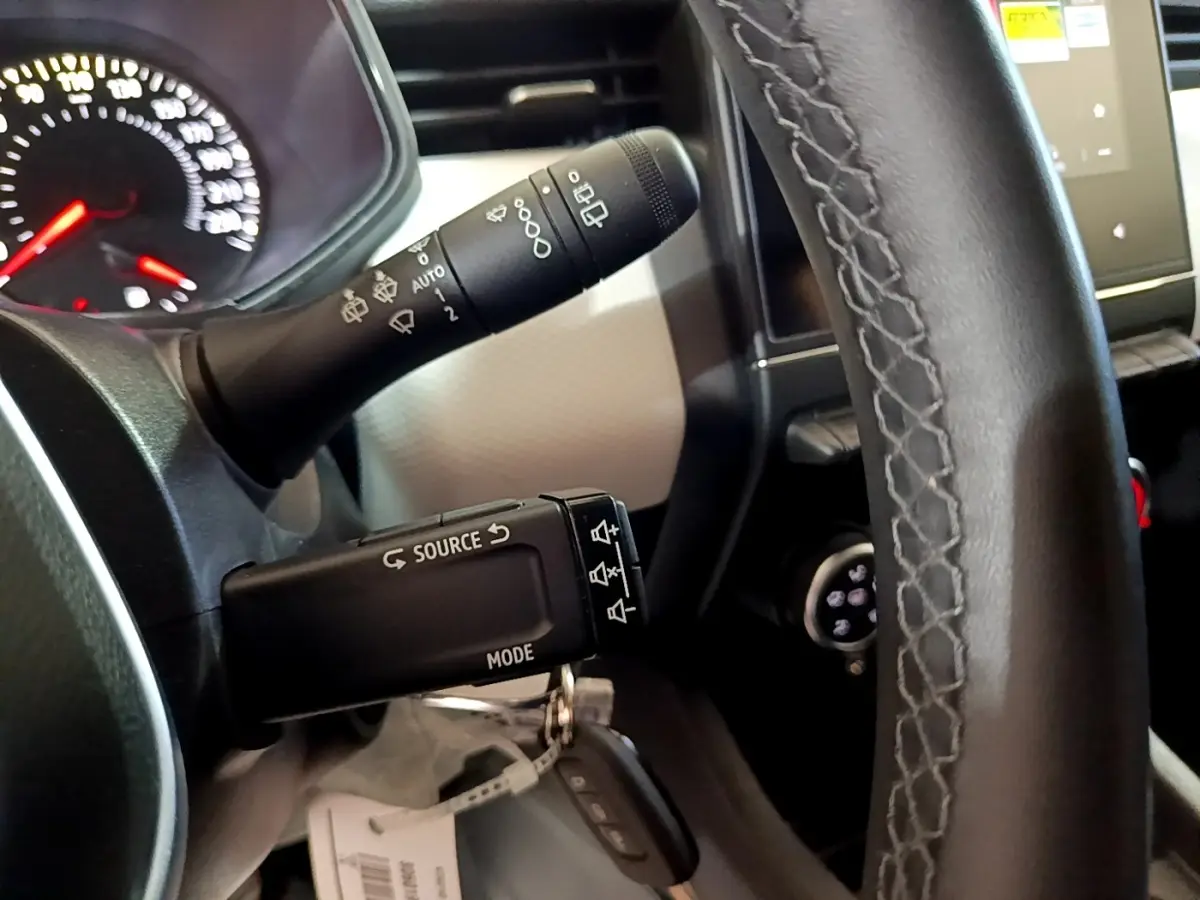 Gros plan sur la commande multifonction noire à gauche du volant en cuir noir de la Renault Clio gris foncé 2022.