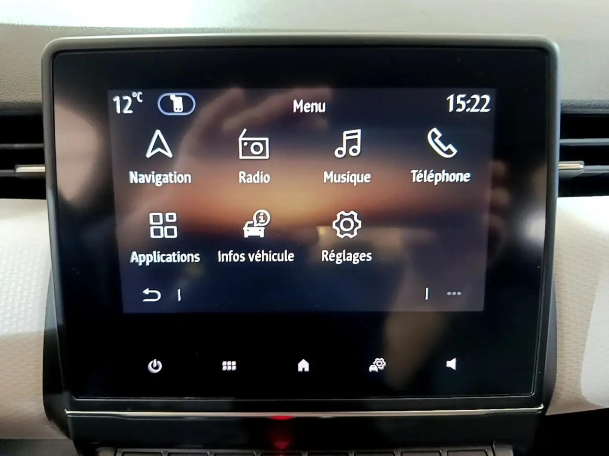 Écran tactile central de la Renault Clio gris foncé, affichant le menu principal avec navigation et réglages.
