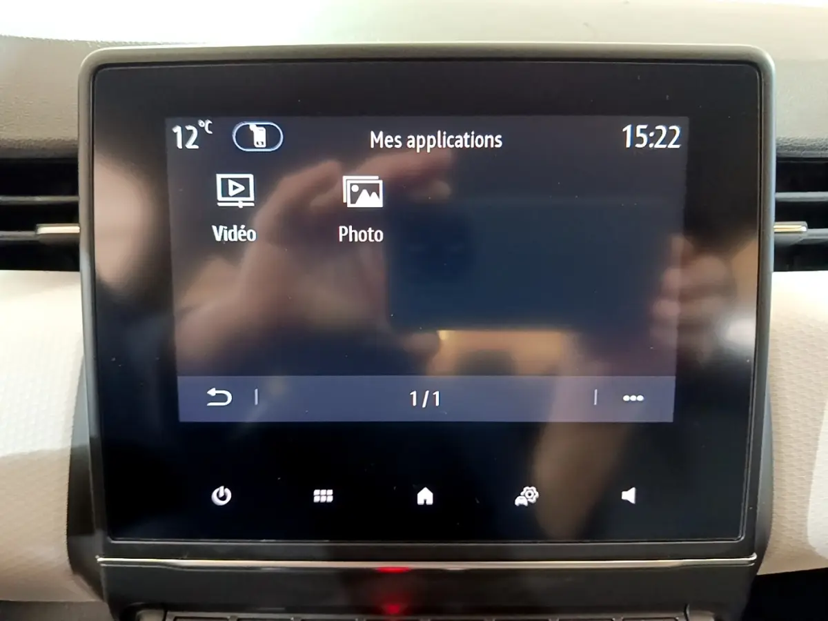 Écran tactile central de la Renault Clio Evolution gris foncé, affichant les applications vidéo et photo, vue de face.