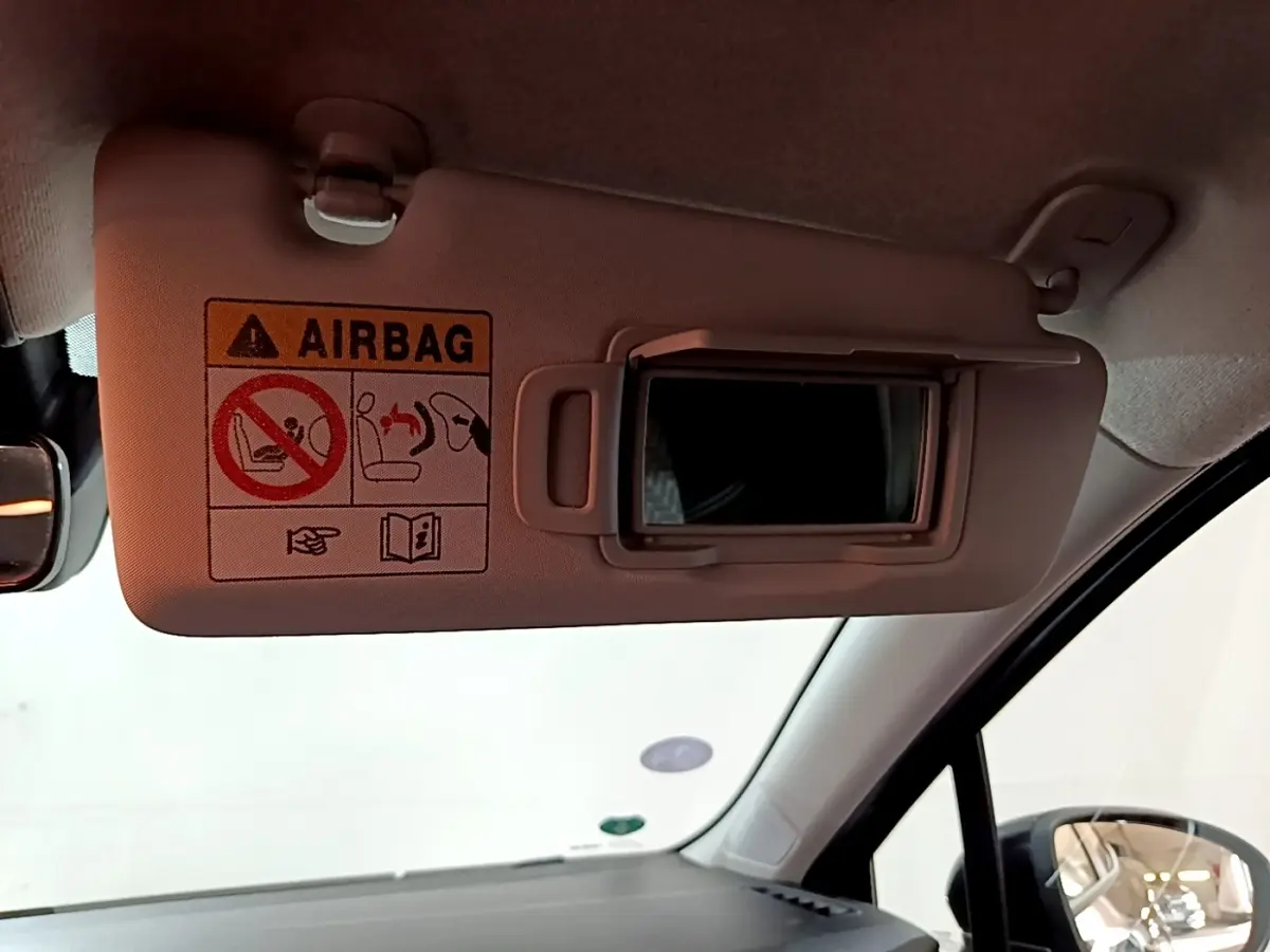 Détail intérieur du pare-soleil côté conducteur avec miroir et avertissement airbag dans une Renault Clio gris foncé.