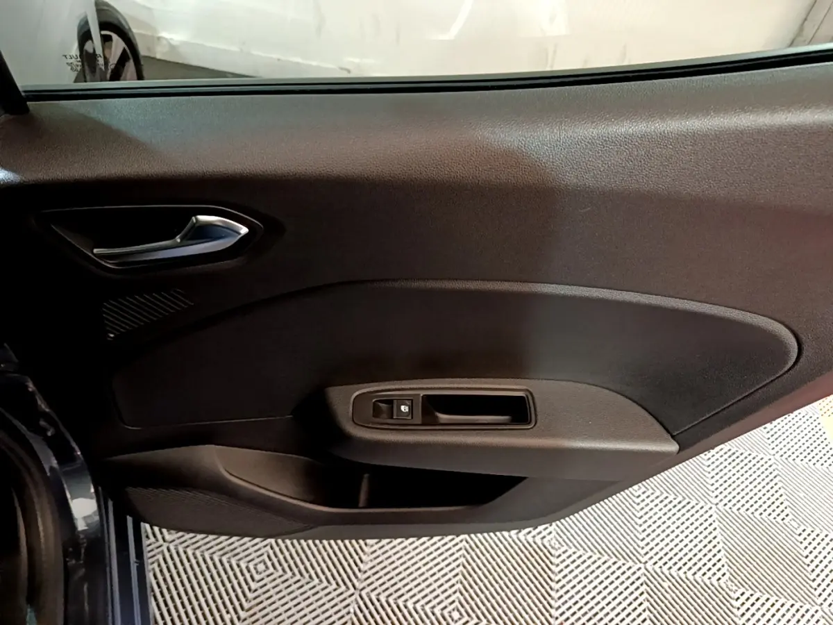 Vue intérieure sur la porte côté conducteur de la Renault Clio gris foncé, avec poignée et commande de vitre électrique.