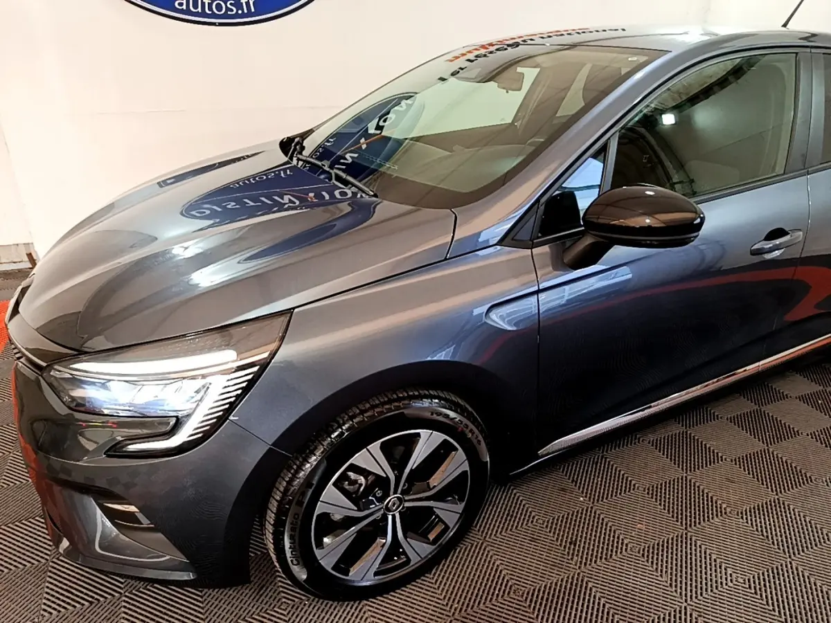 Vue 3/4 avant droit d'une Renault Clio Evolution gris foncé avec phares LED et jantes alliage distinctives.