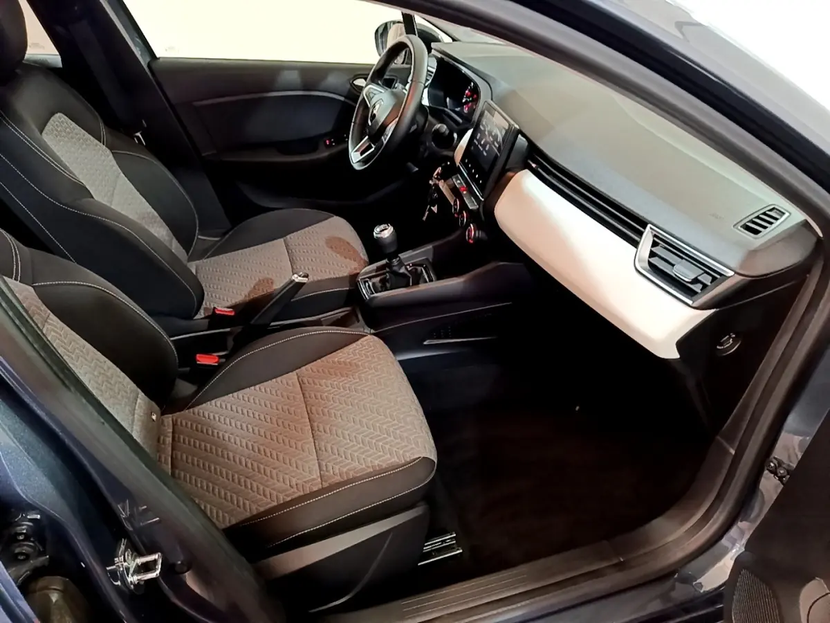 Intérieur avant droit de la Renault Clio gris foncé 2022, montrant sièges tissu bicolore et tableau de bord avec écran tactile.