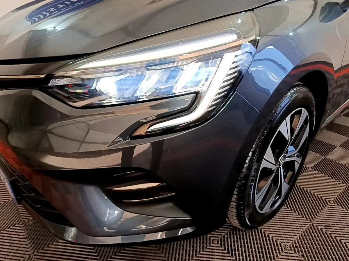 Gros plan sur l'avant droit gris foncé d'une Renault Clio 2022 avec phares LED et jante alliage moderne.