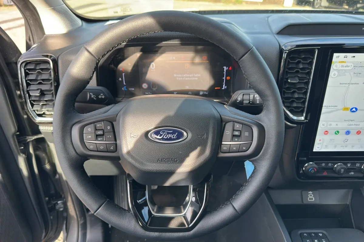 Vue rapprochée du volant cuir multifonctions et du tableau de bord numérique du Ford Ranger gris carbone 2026.