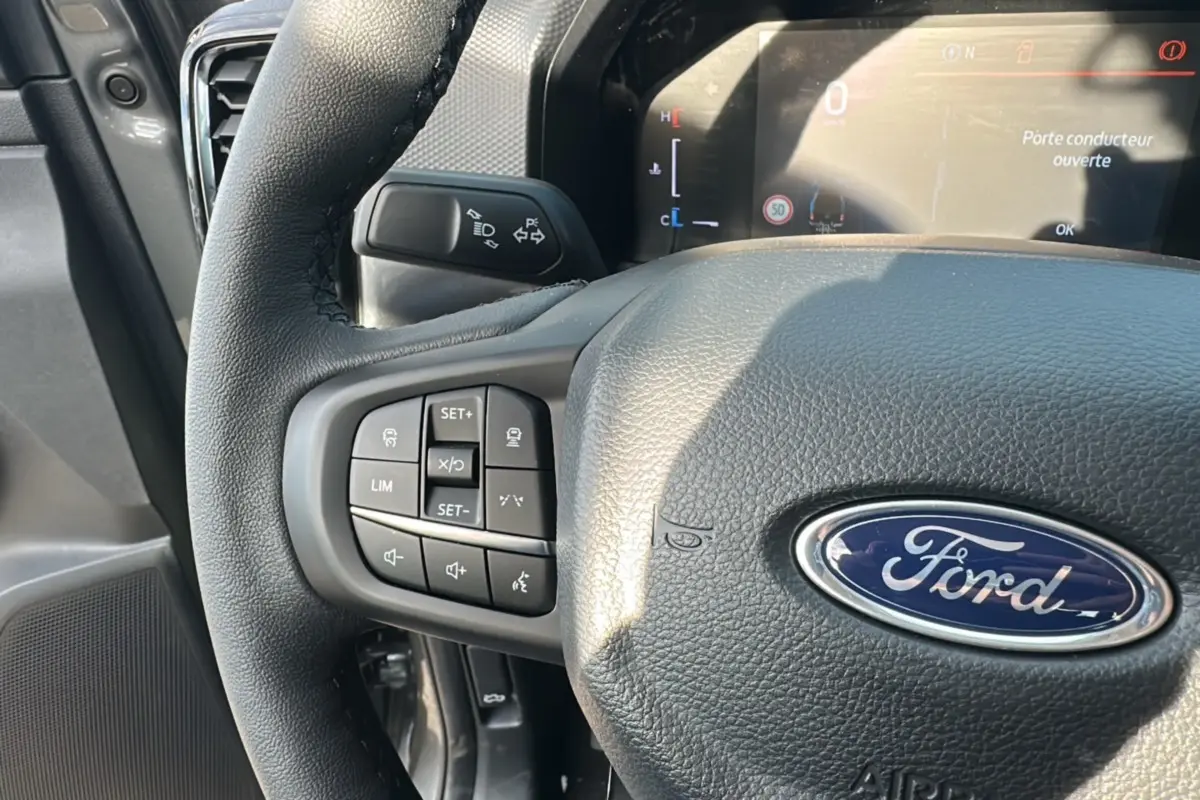 Gros plan sur le volant cuir noir du Ford Ranger 2026 avec commandes multifonctions et tableau de bord numérique.